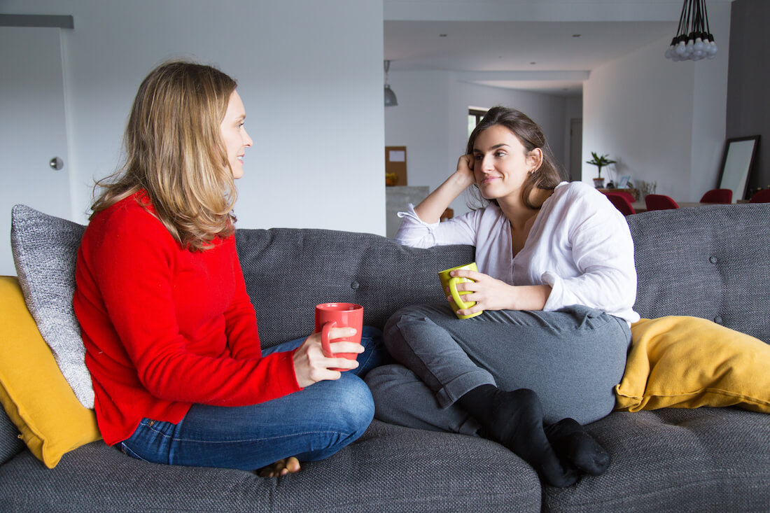 Chatted over. Living Room friends chat. Two women on Couch. Siblings Fighting over a Remote. Two friends are chatting.