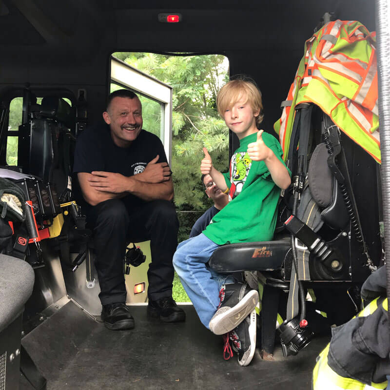 Boy with Autism inside firetruck with firefighter.
