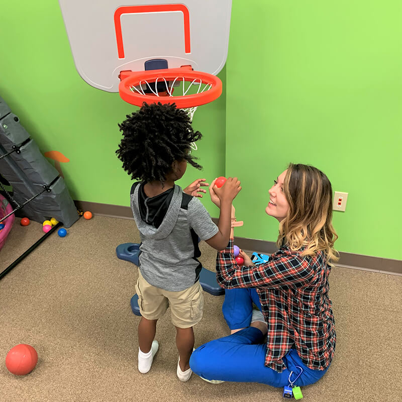 Child with Autism engaged in play therapy with woman.