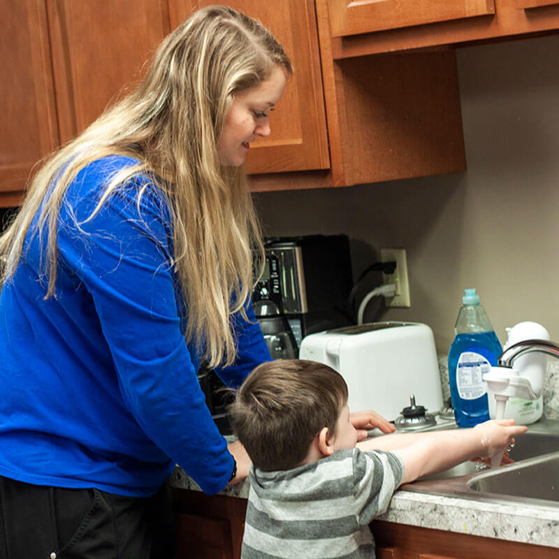 Katie helps child with autism wash his hands.