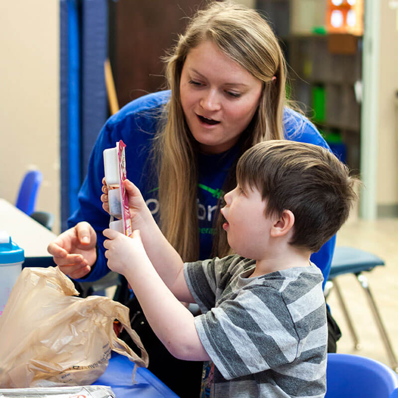 Katie helps child with autism open his lunch.