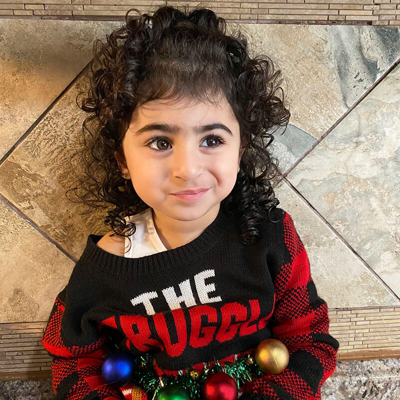 Tasneem, girl with autism, sitting on counter with silly smerk.