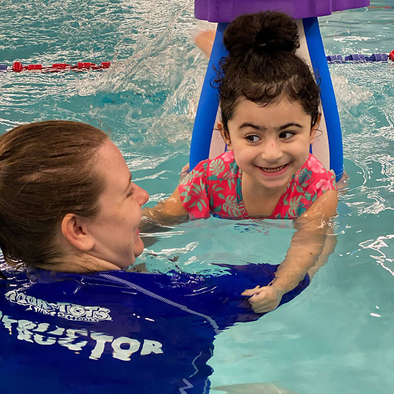 Tasneem, girl with autism, swimming with her instructor with a big smile on her face.