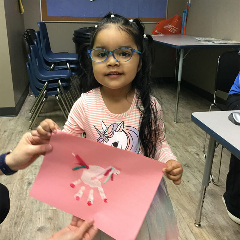 Girl with photo of her hand-made unicorn.