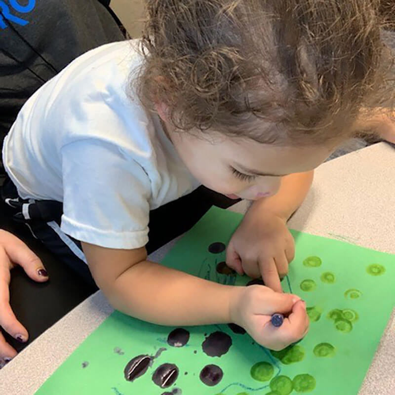 Boy with autism working on fine motor skills with crayons and coloring.