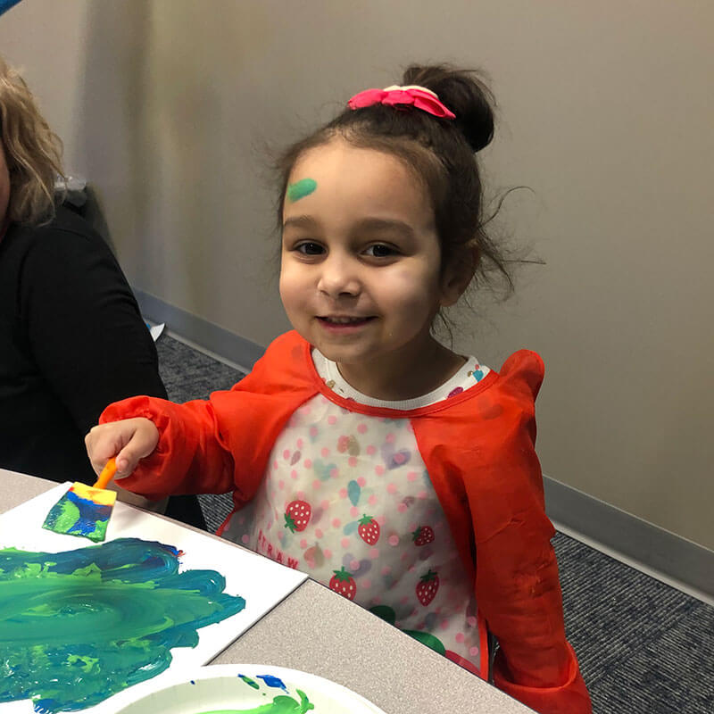 Girl with autism painting blue and green picture.