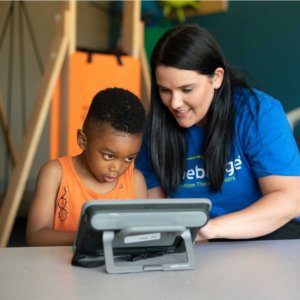 Hopebridge Autism Therapy Centers therapist provides therapy to child on spectrum with tablet