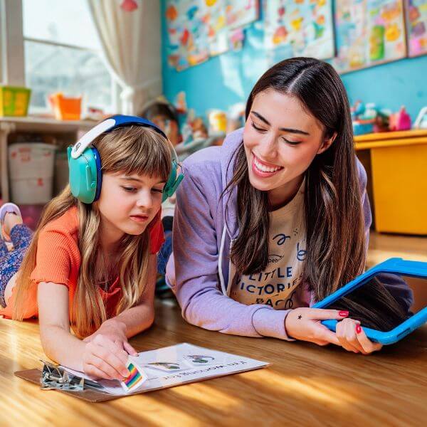 A girl with autism wearing Noise cancelling headphones while working with a Hopebridge ABA Therapist.