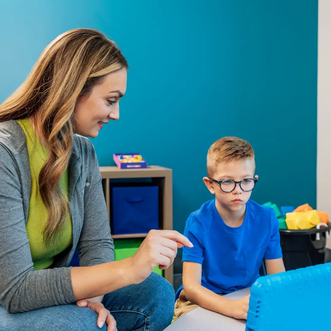 Child using an AAC device with Hopebridge staff member