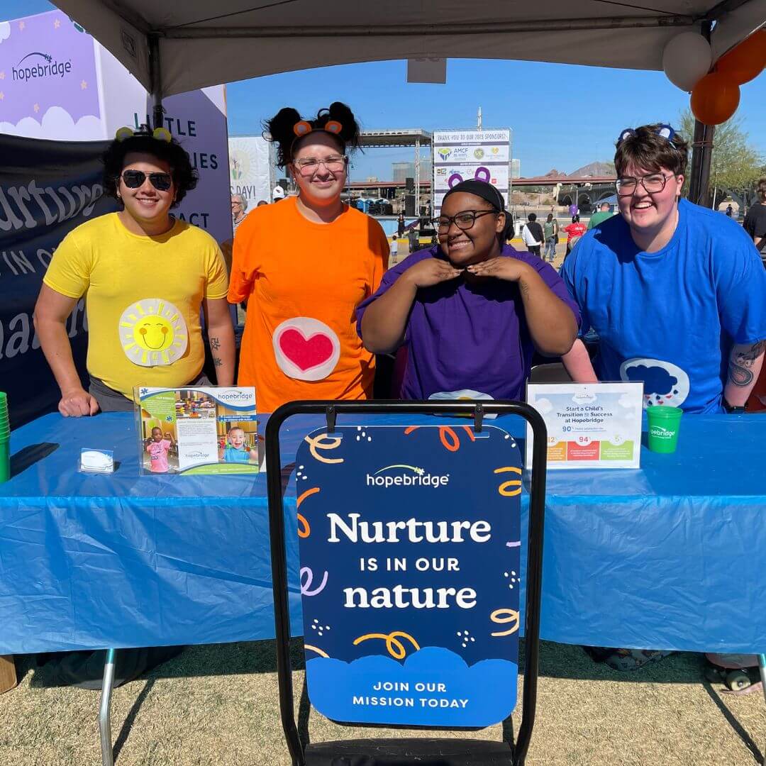 Hopebridge team at a community event with colorful shirts promoting their mission: 'Nurture is in our nature
