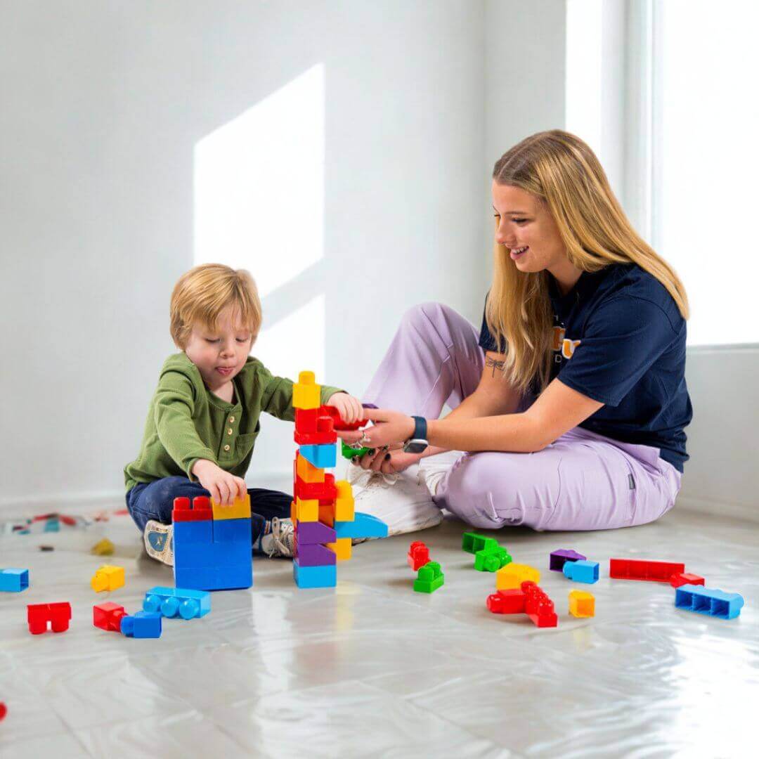 A Hopebridge therapist engages a young child in play therapy with colorful blocks, fostering growth through learning and fun