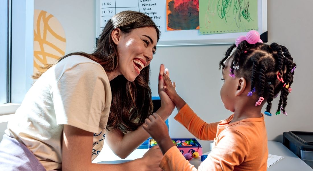 RBT and child giving each other a high five during an ABA therapy session at Hopebridge.