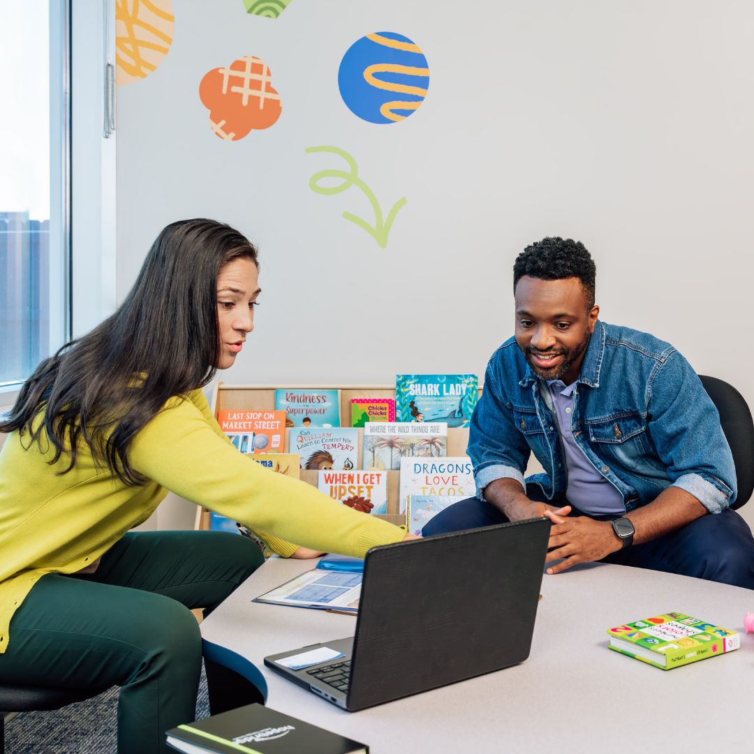 BCBA and father looking at a computer together at an ABA therapy center during a family guidance center.