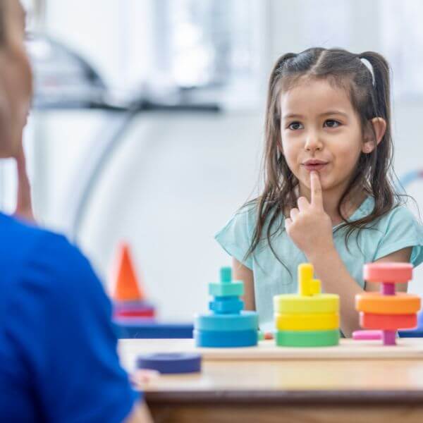 Photo of child learning how to form sounds and words using different toys and tools during speech therapy.